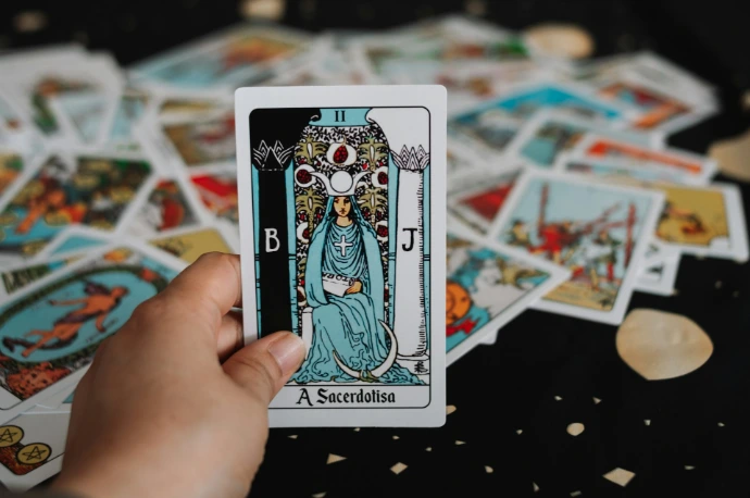 Hand holding a tarot card over a spread.
